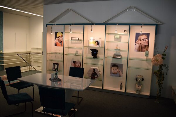 Heller Beratungsraum mit Glastischen, Stühlen und Vitrine zum Thema Hörakustik.